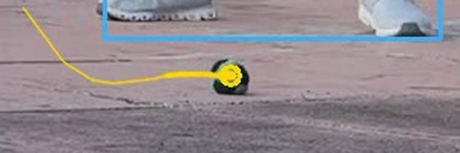 Close-up of a yellow tracker dot sitting on top of a real footbag on the pavement